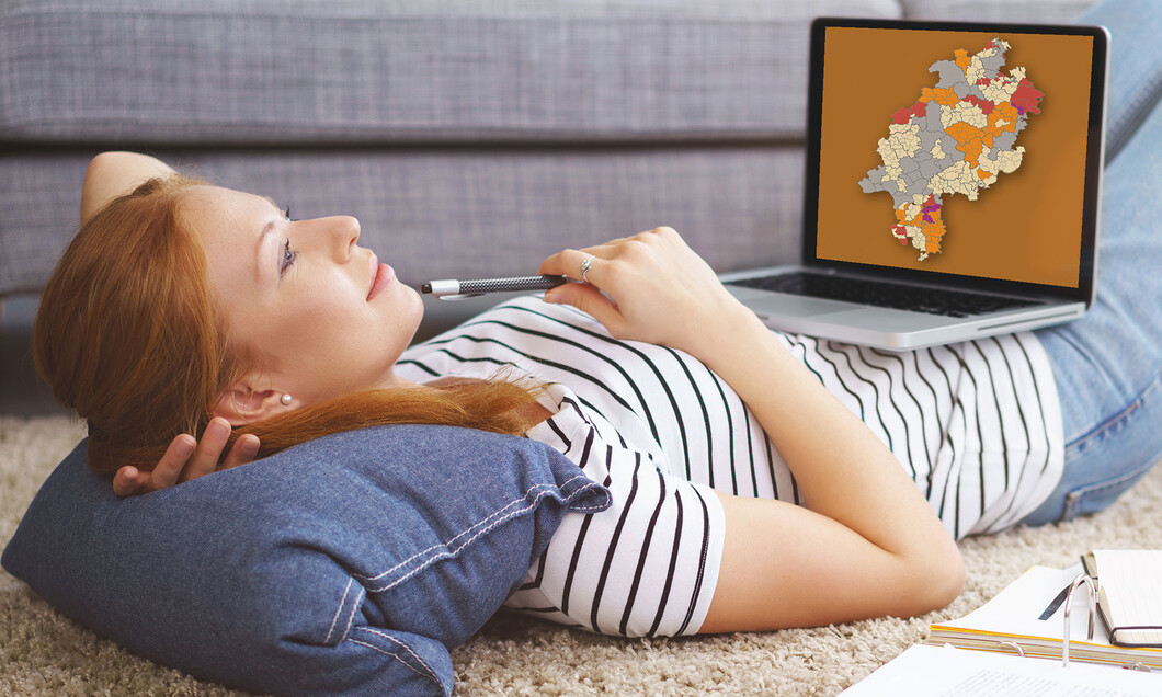 Eine liegende Studentin mit aufgeklapptem Laptop auf dem Bauch