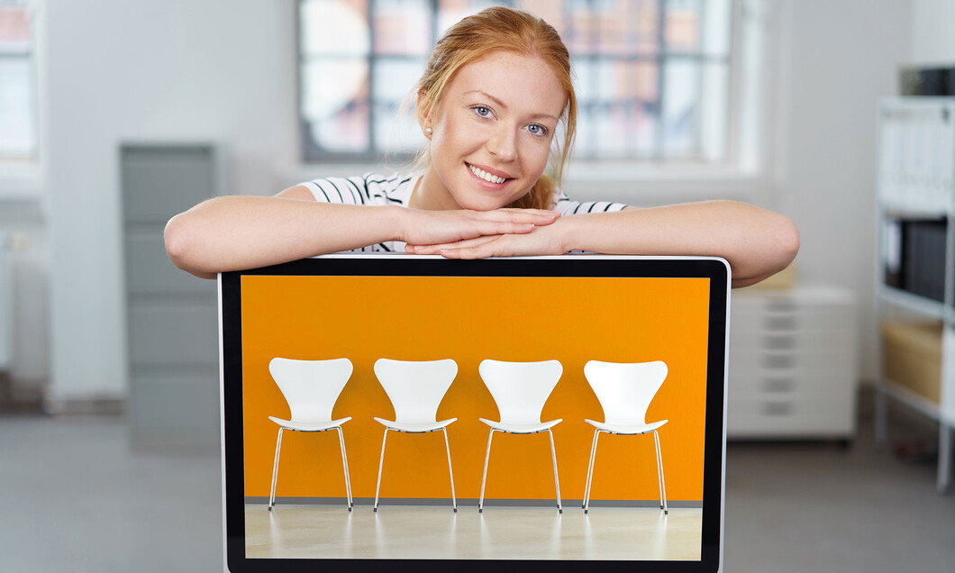 Eine Studentin stützt die Arme auf einen Monitor, der leere Stühle zeigt